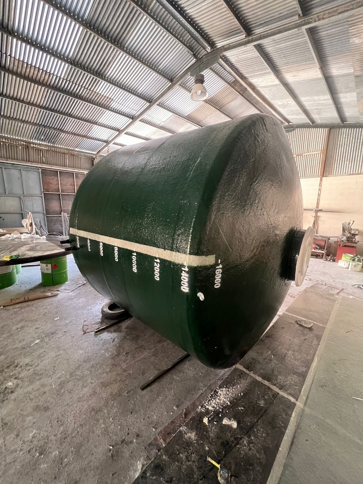 Un gran tanque verde está en un almacén.