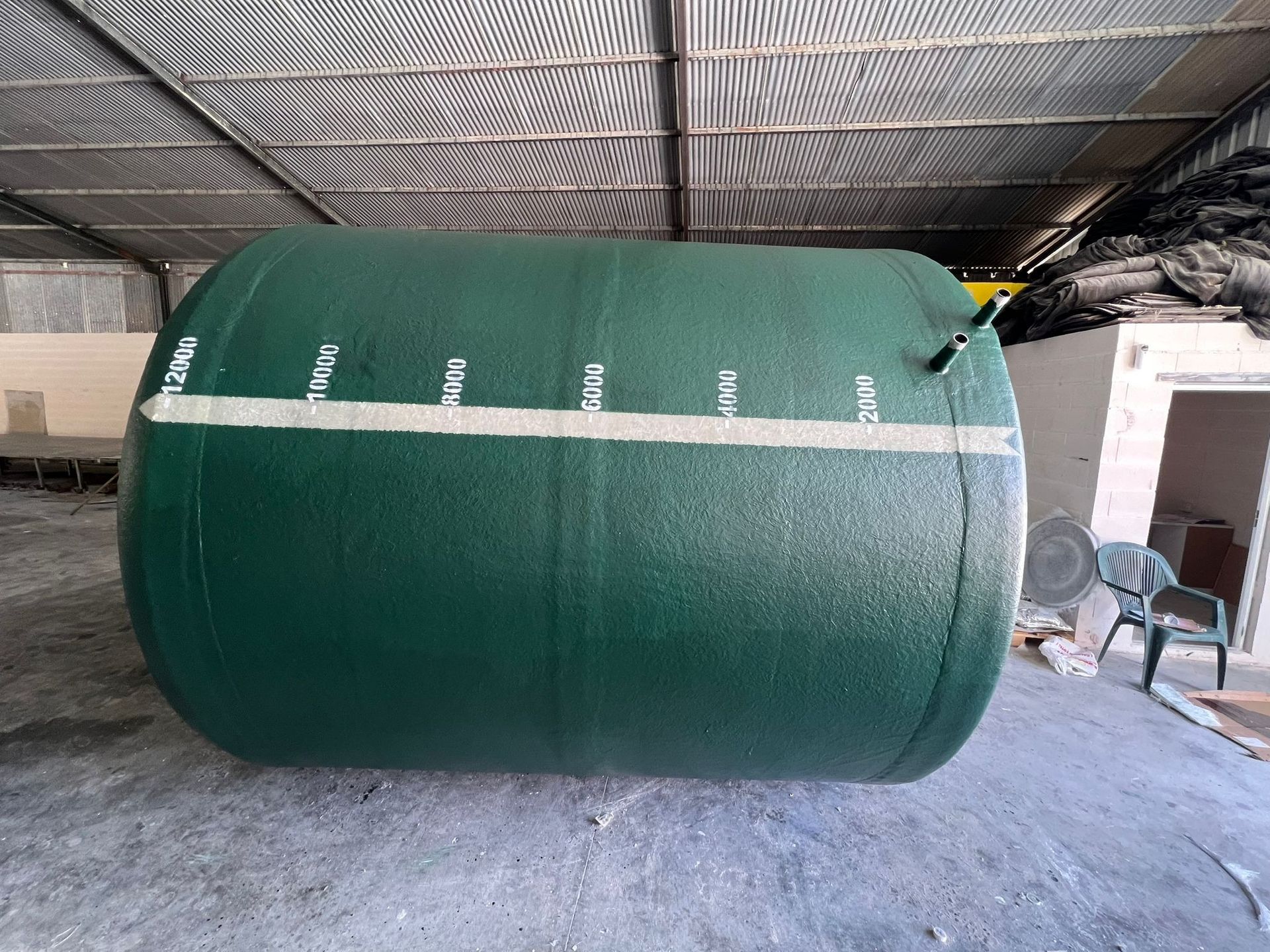 Un gran cilindro verde se encuentra en un almacén.