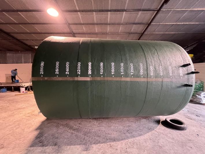 Un gran tanque verde está en un almacén.