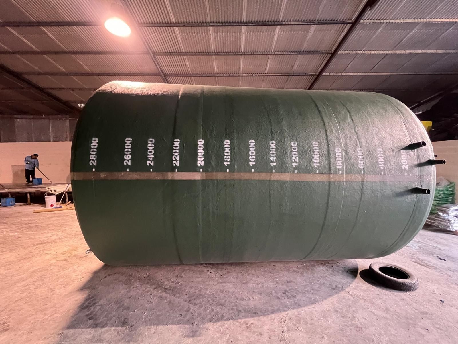 Un gran tanque verde está en un almacén.