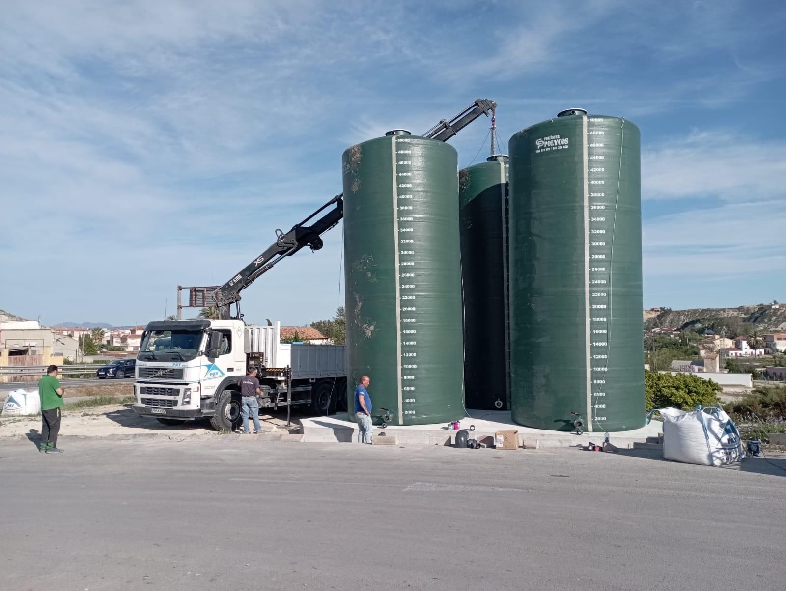 Un gran tanque gris está situado sobre una superficie de hormigón frente a un edificio.