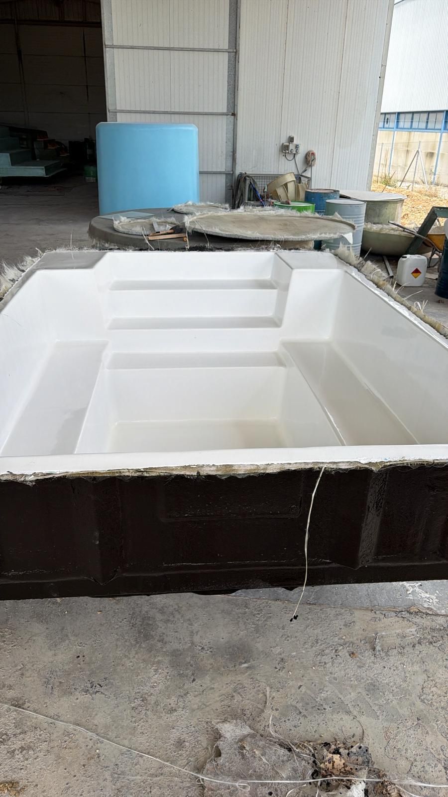 Gran molde o cubeta rectangular de espuma blanca en un taller con herramientas y materiales al fondo.