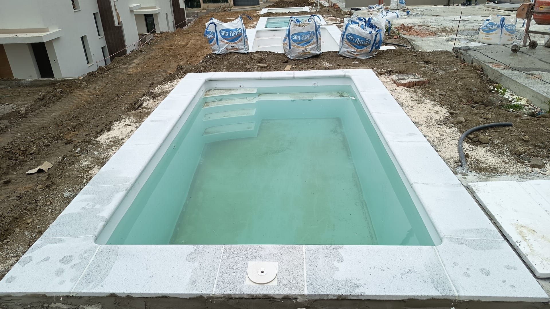 Piscina rectangular enterrada en construcción, rodeada de hormigón y tierra.