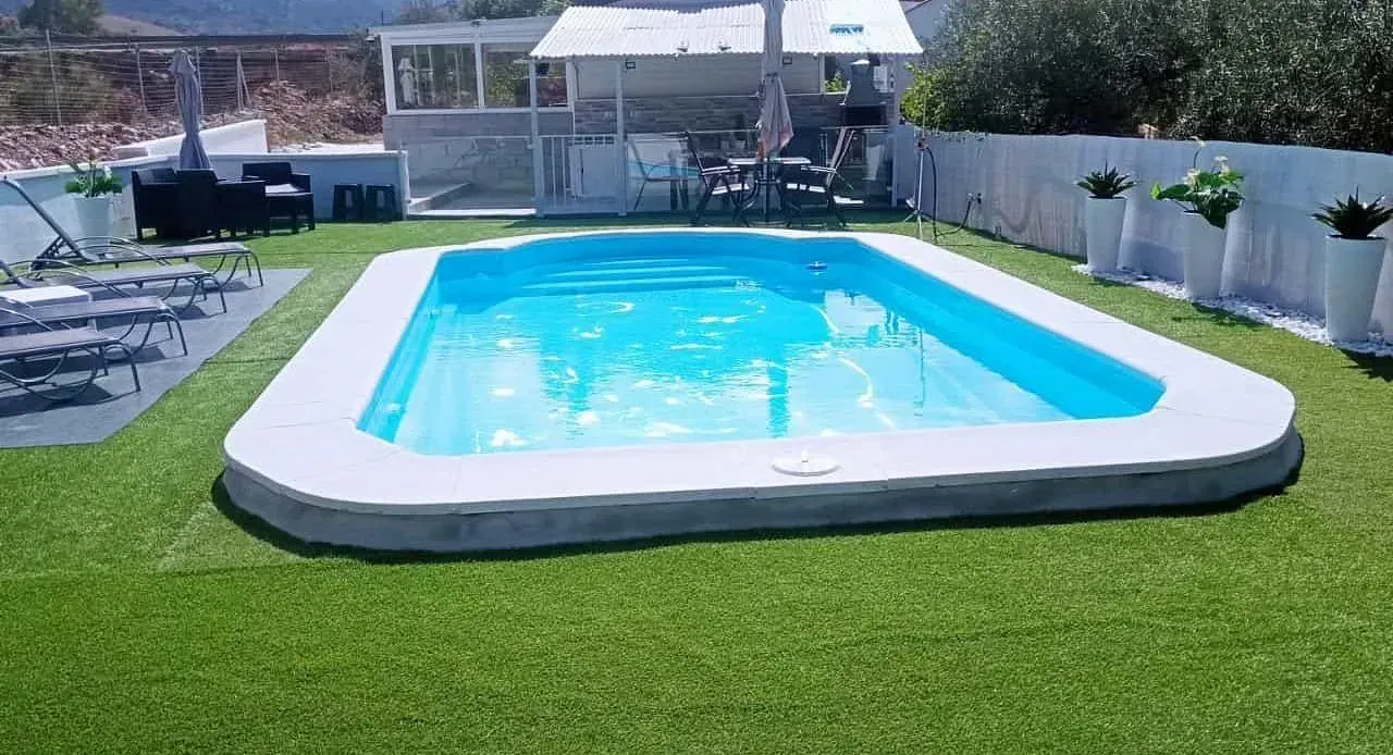 Una gran piscina está rodeada de un exuberante césped verde.