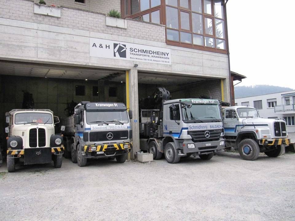 Vier geparkte Lieferwagen vor einer Garage mit einem A&H Schmidhuber-Schild