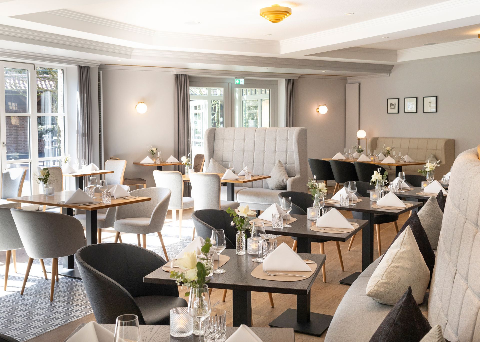 Een licht, modern restaurantinterieur met elegante grijze stoelen, gedekte tafels en sfeervolle verlichting.