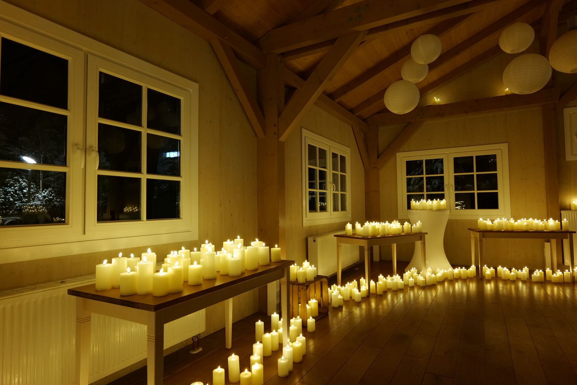 Ein weißes Klavier, umgeben von unzähligen Kerzen in einem dunklen Raum, erzeugt ein warmes, stimmungsvolles Licht.