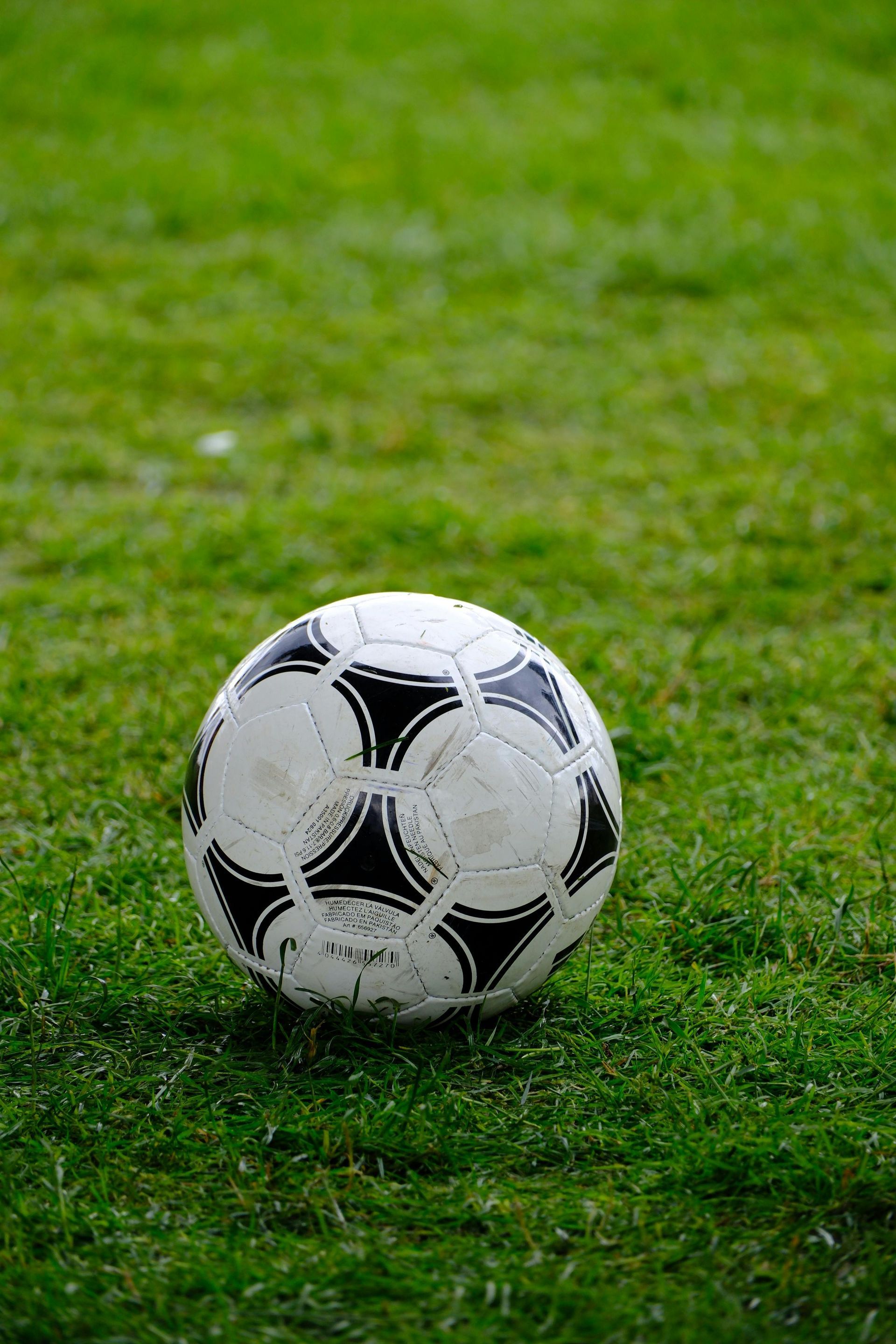 Er ligt een zwart-witte voetbal op groen gras.