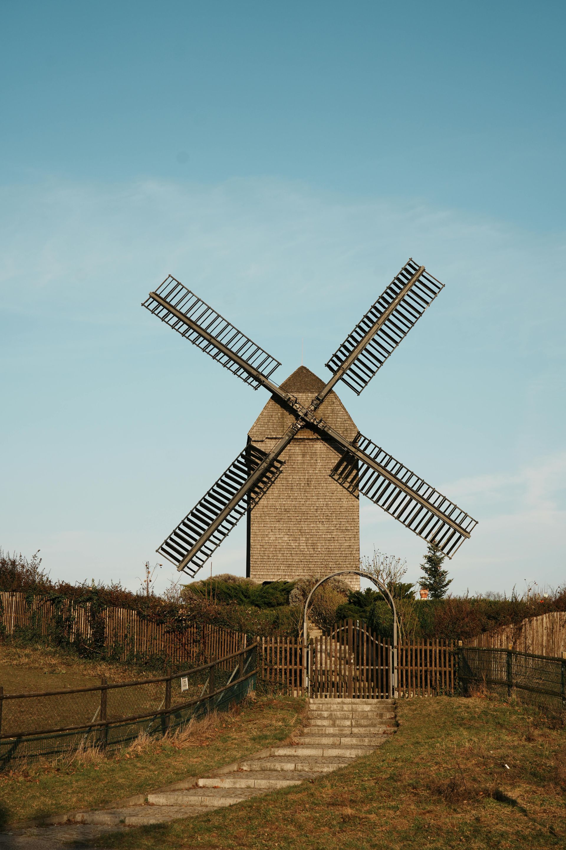 Lichtdurchfluteter Speisesaal mit Reihen von Tischen und grau gepolsterten Stühlen neben großen Fenstern mit Blick auf ein Backsteingebäude.