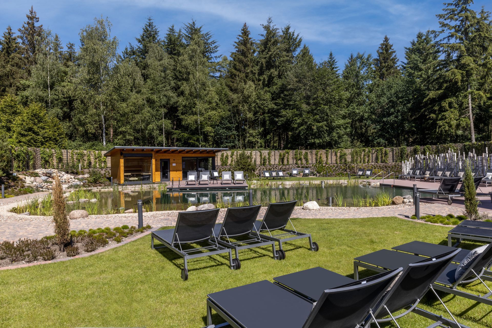 Een helder verlichte vergaderzaal met rijen tafels en houten stoelen die naar een groot, aan de muur bevestigd scherm zijn gericht.