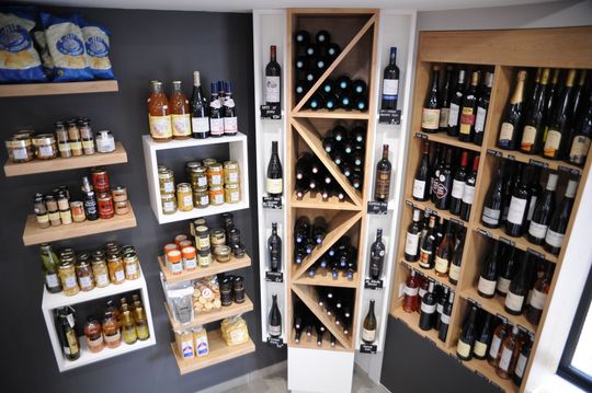 Rayonnages de vins et spiritueux avec bouteilles et canettes dans une petite vitrine de magasin.