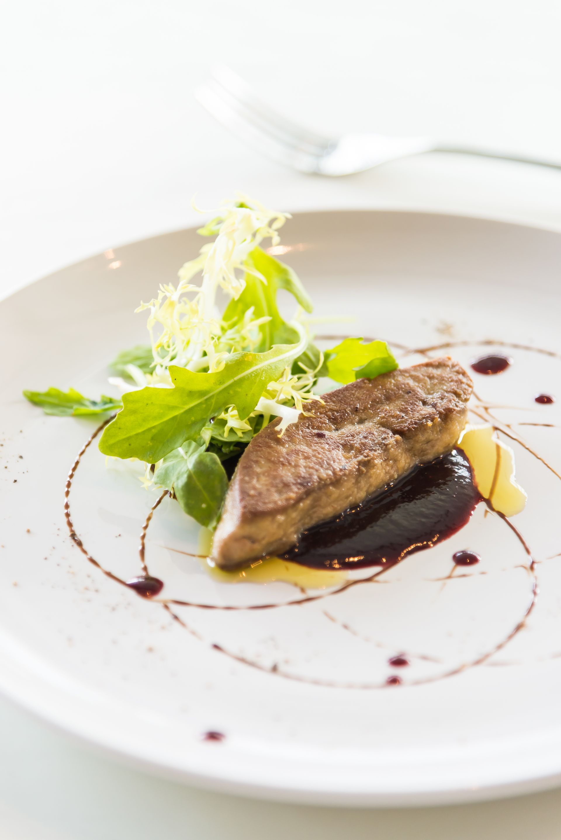 Poisson poêlé gastronomique servi avec des légumes verts et une sauce sur un plat blanc