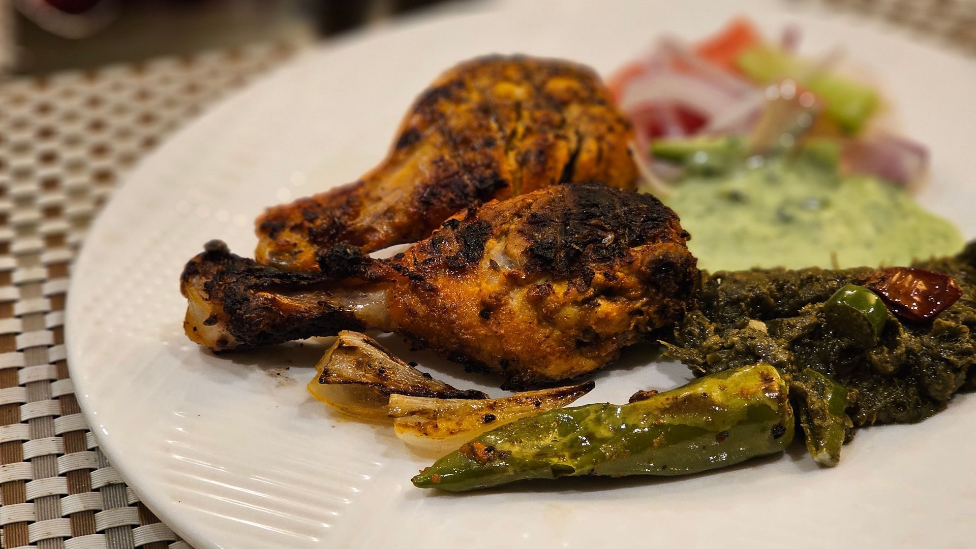 Cuisse de poulet grillée avec poivrons grillés et salade sur une assiette blanche