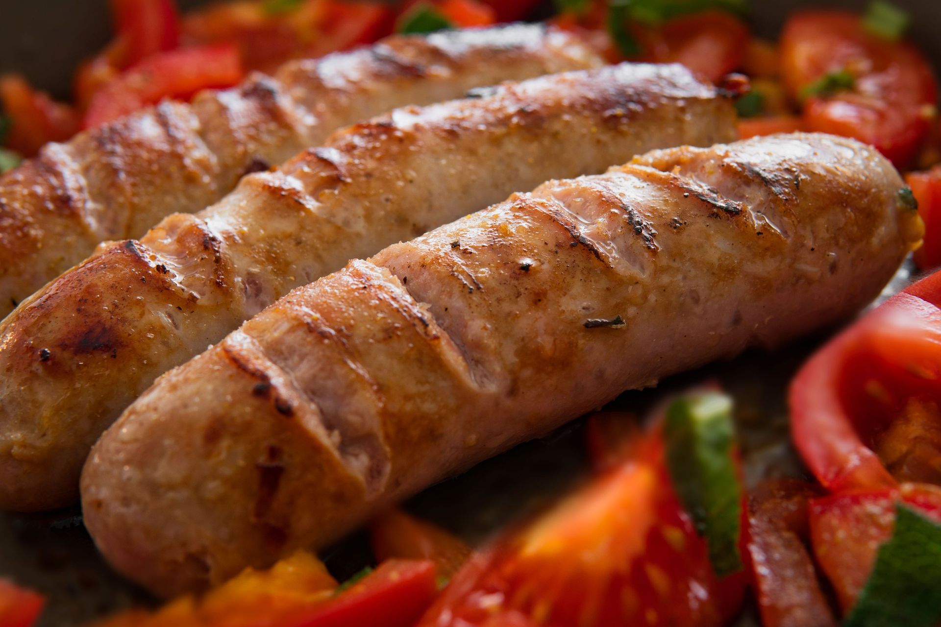 Saucisses grillées sur un plateau avec des poivrons et des tomates en tranches