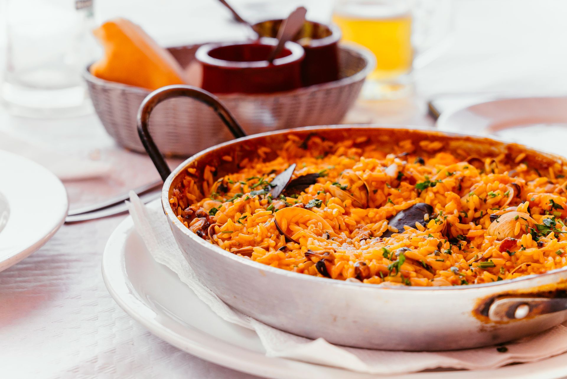 Plat de riz cuit au four dans une poêle sur une table, avec des bols de sauce et une garniture d'orange à proximité.