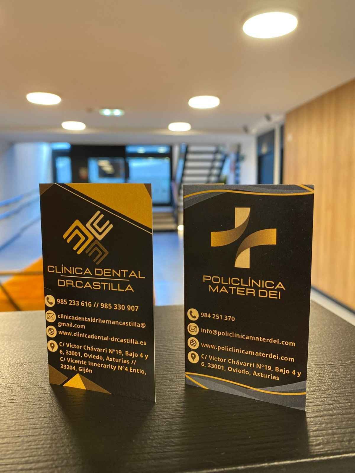 Dos tarjetas de visita negras y doradas reposan sobre una superficie oscura en un vestíbulo bien iluminado.