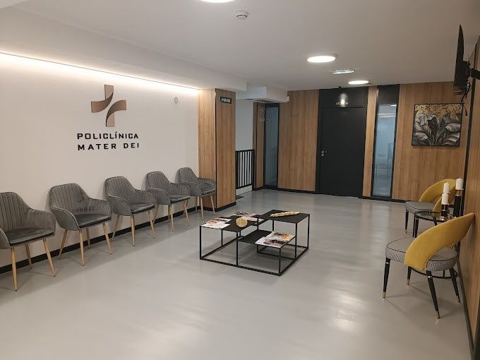 Una moderna sala de espera de una clínica médica con sillas grises, una mesa de centro baja y el logotipo