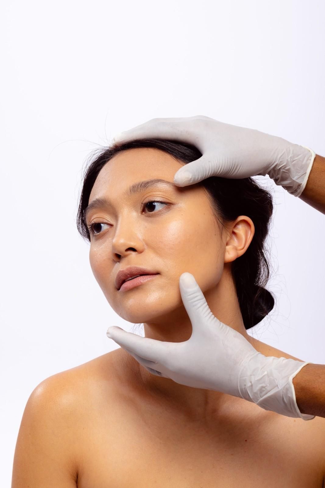 Una persona de cabello oscuro aparta la mirada mientras unas manos con guantes médicos blancos le sujetan 