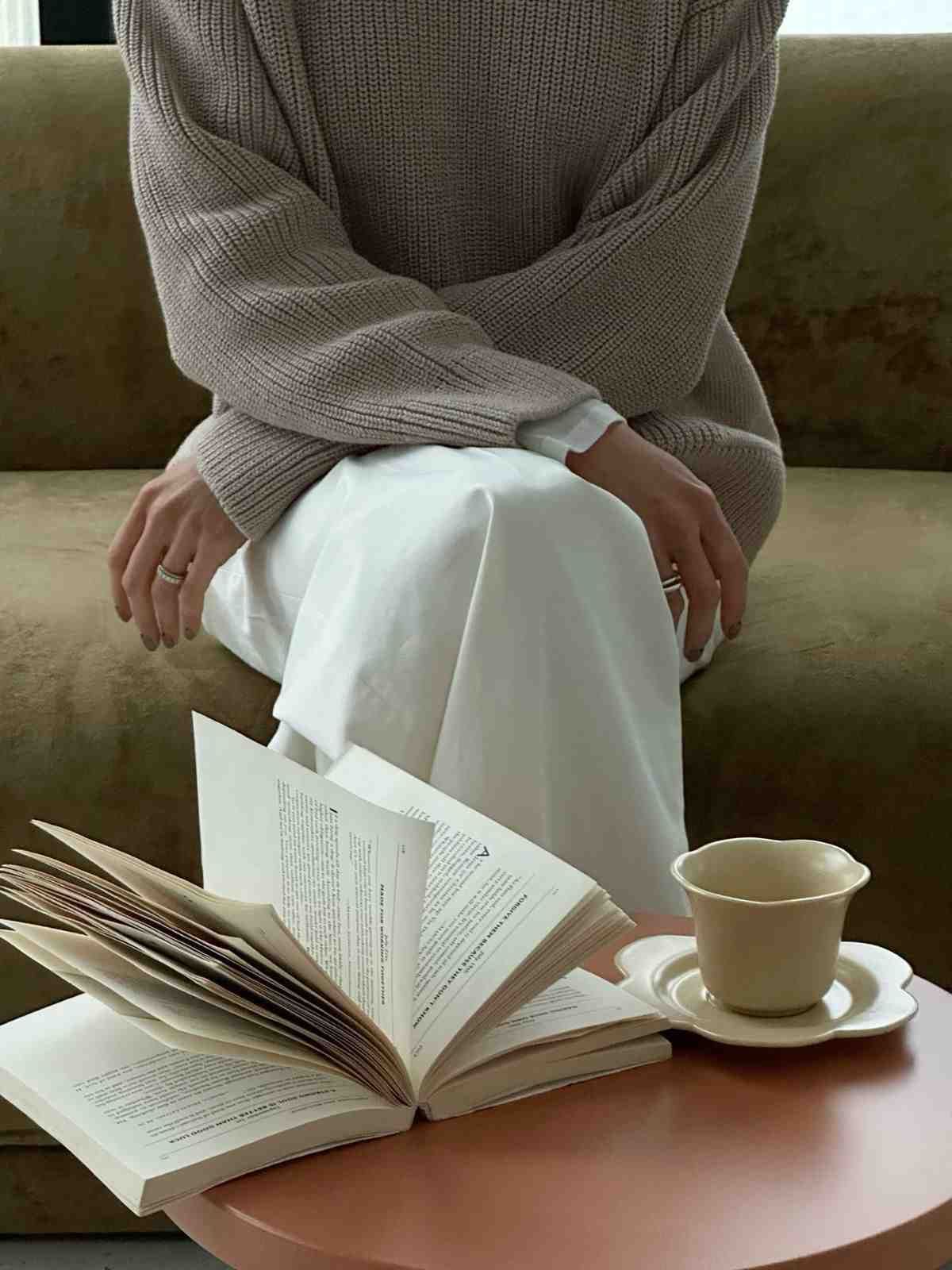 Una persona está sentada en una silla con las manos entrelazadas, hablando con alguien que toma notas en un portapapeles