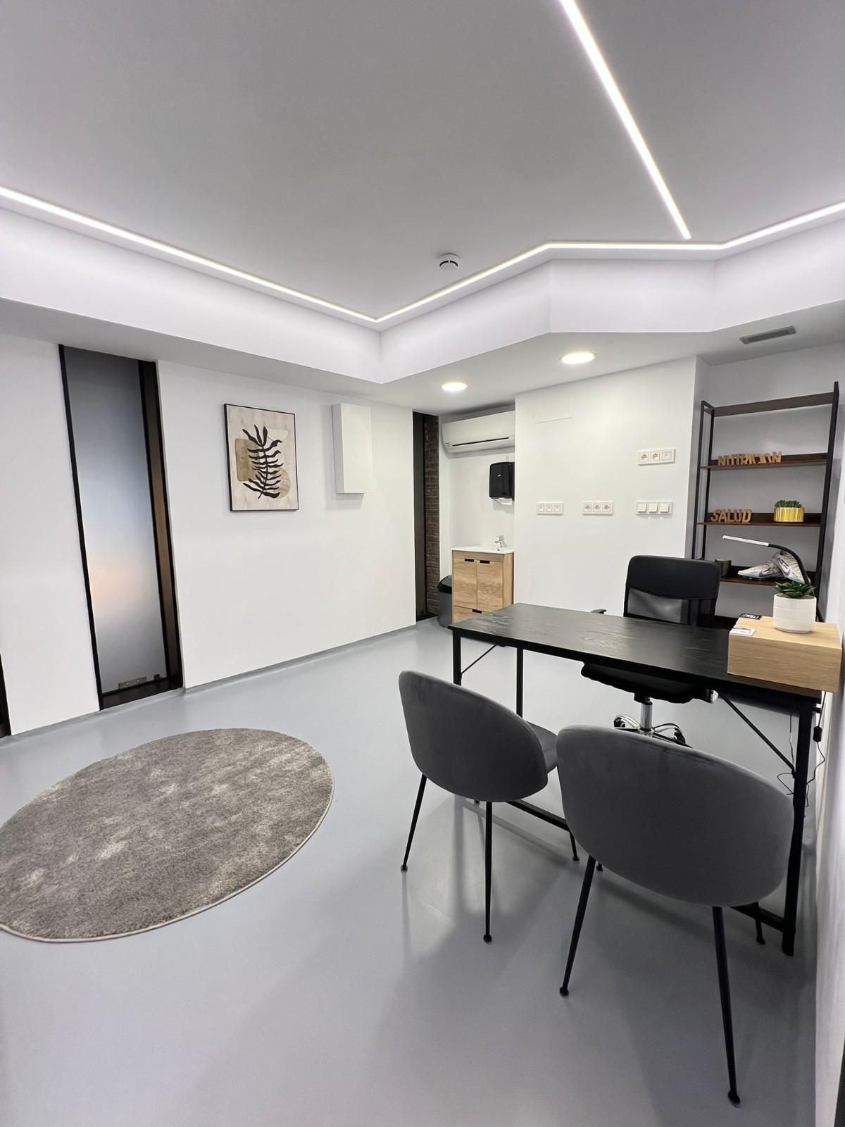 Un par de zapatillas blancas y dos mancuernas azules dispuestas sobre un fondo verde azulado liso.