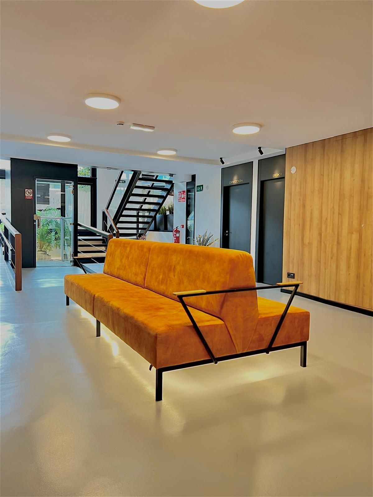 Primer plano del rostro de una persona junto a una ramita de orquídeas blancas sobre un fondo blanco suave.