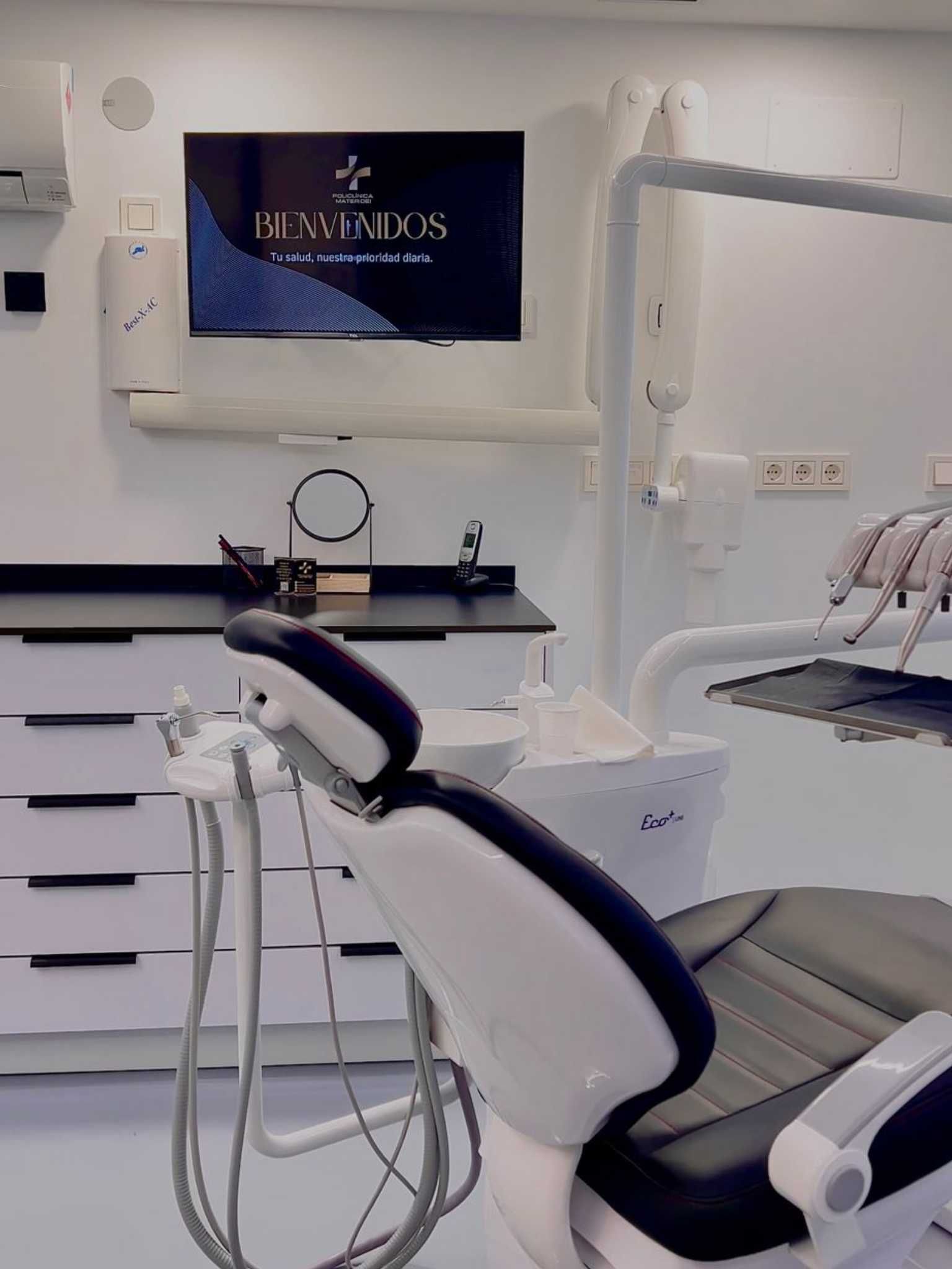 Una moderna sala de consulta dental con un sillón reclinable blanco y negro, instrumental dental y una pantalla