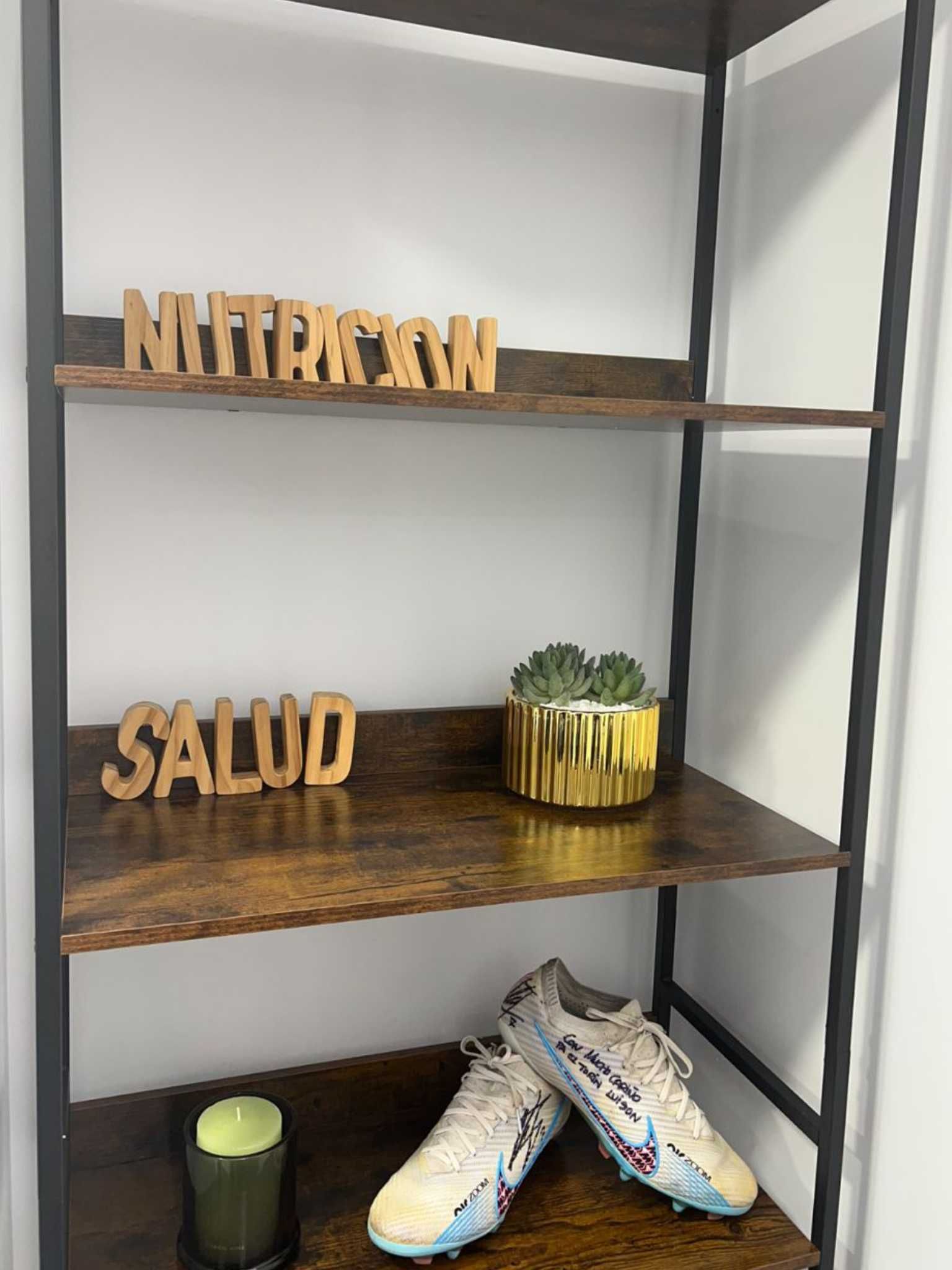 Una persona sonriente vestida con ropa deportiva sostiene un tazón de ensalada y una pieza de fruta