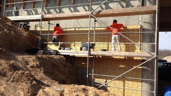 Eine Gruppe Bauarbeiter arbeitet an einer Ziegelmauer