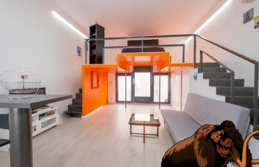 Interior de loft moderno con entrepiso naranja, escaleras grises y espacio de estar abierto.