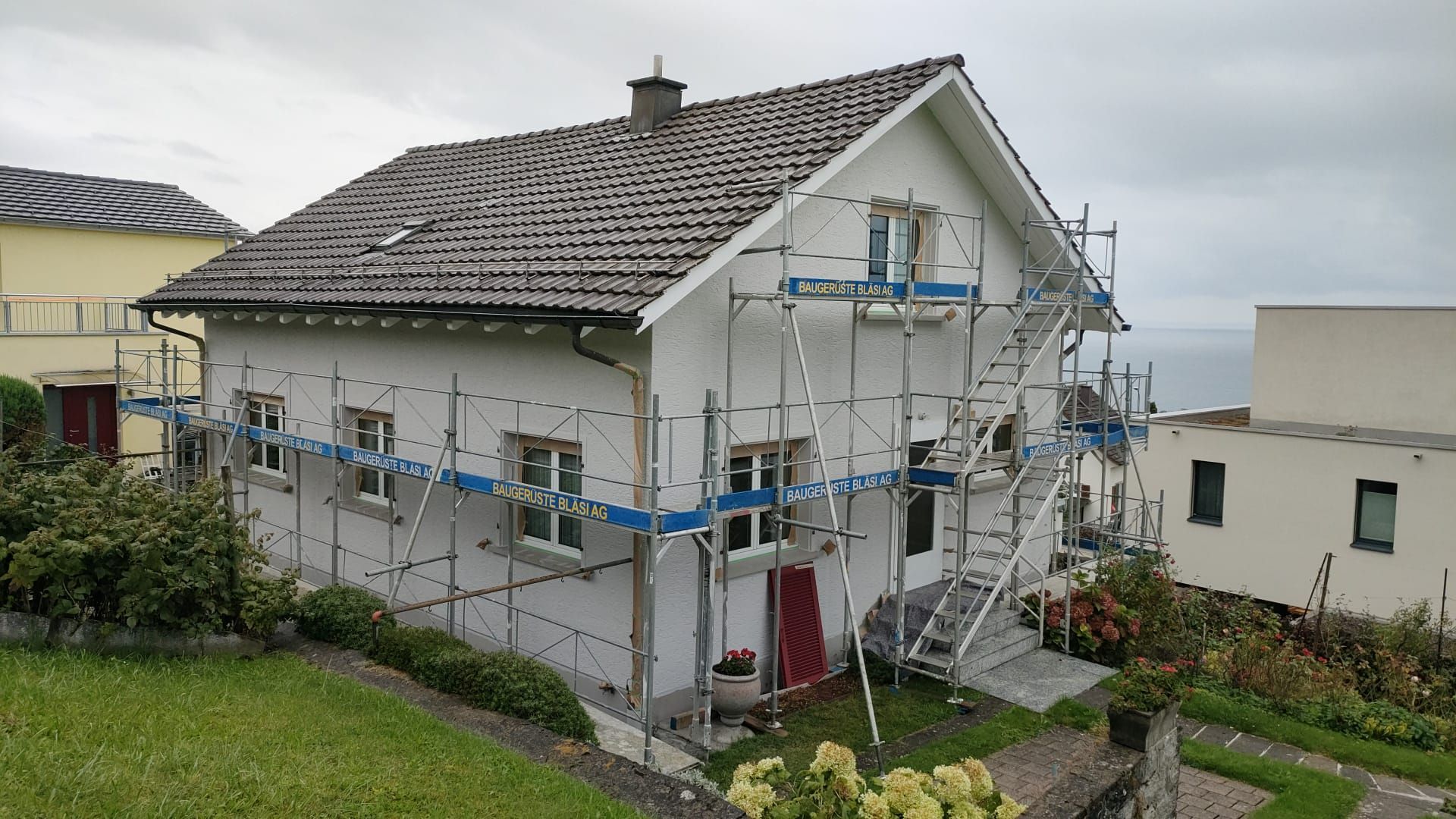Leerer Raum mit Akzentwand aus Holzpaneelen, weisser Tür und grauem Boden.