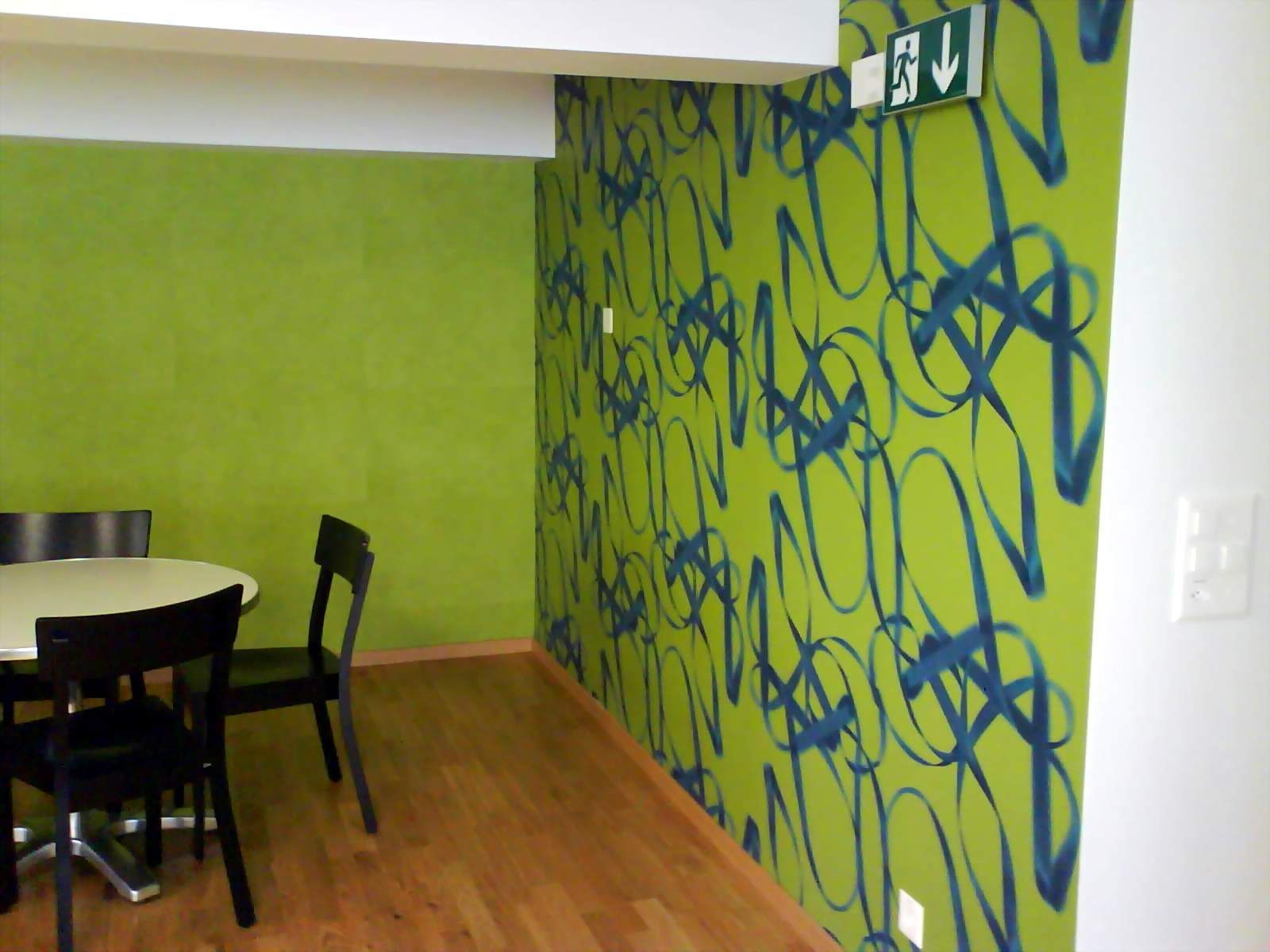 Eine Person streicht einen Raum mit einer Rolle weiss.