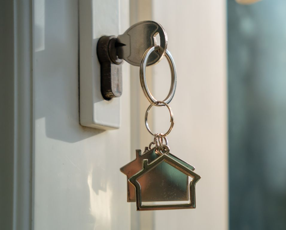 Clé dans la serrure de la porte avec porte-clés en forme de maison