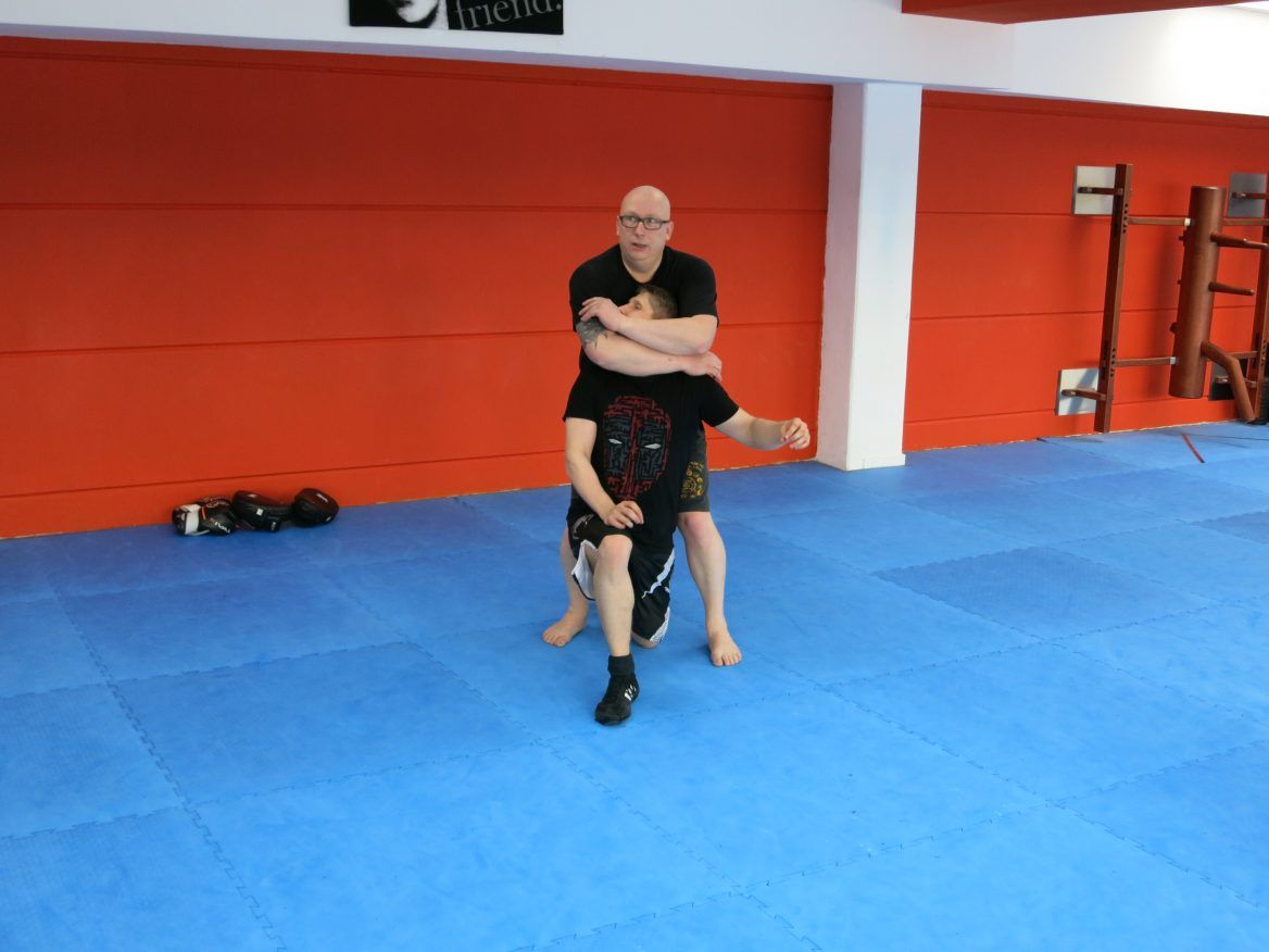 Zwei Kampftrainer und ein Schüler beim Üben auf der Matte