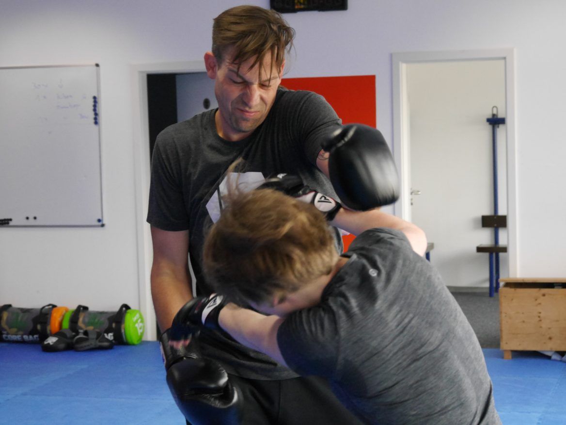Zwei Kampftrainer und ein Schüler beim Üben auf der Matte
