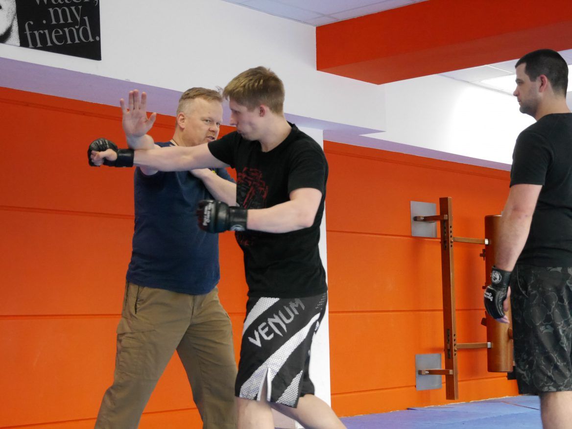 Zwei Kampftrainer und ein Schüler beim Üben auf der Matte
