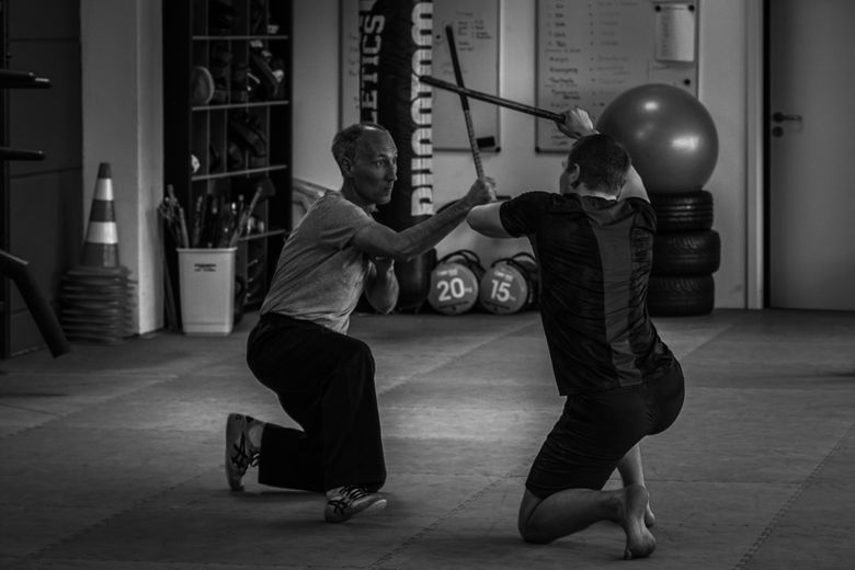 Zwei Kampfsporttrainer demonstrieren den Stockkampf auf den Knien