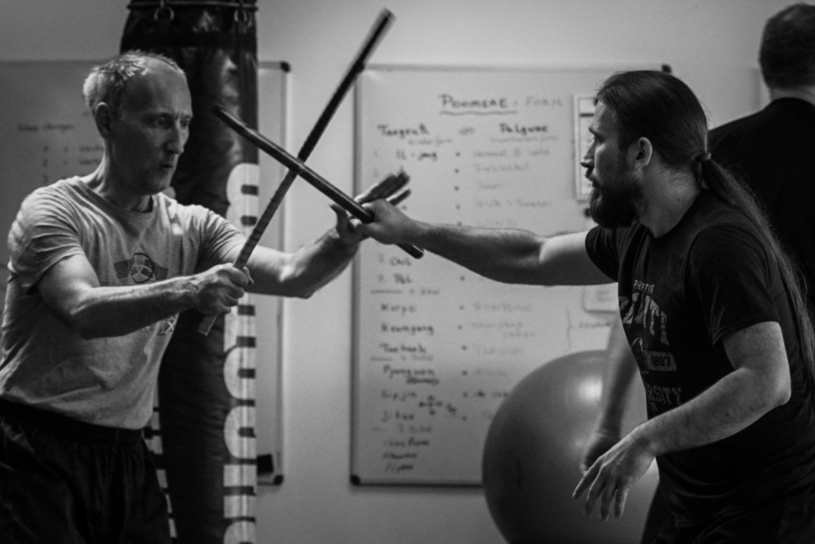 Zwei Kampftrainer und ein Schüler beim Üben auf der Matte