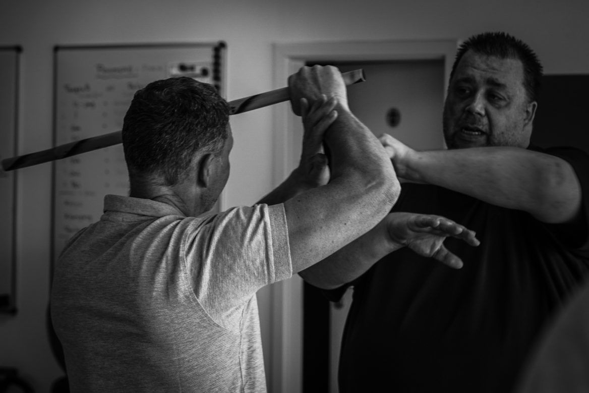 Zwei Kampftrainer und ein Schüler beim Üben auf der Matte