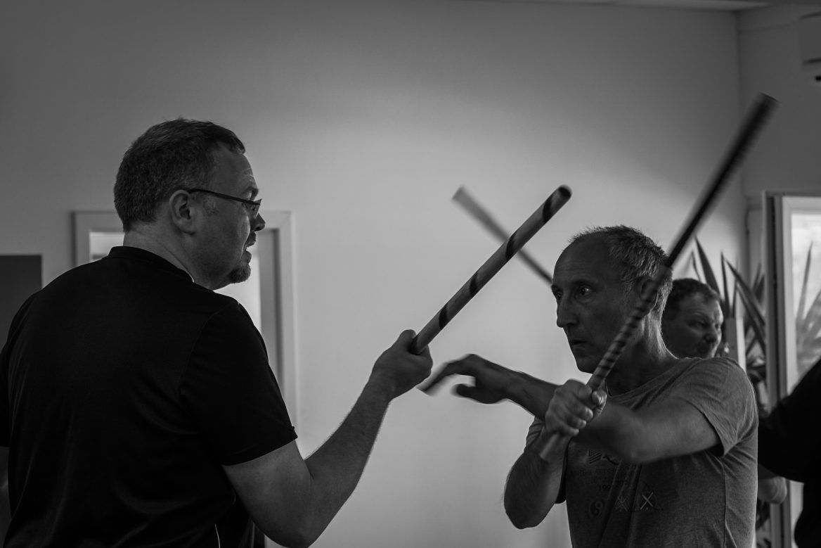 Zwei Kampftrainer und ein Schüler beim Üben auf der Matte