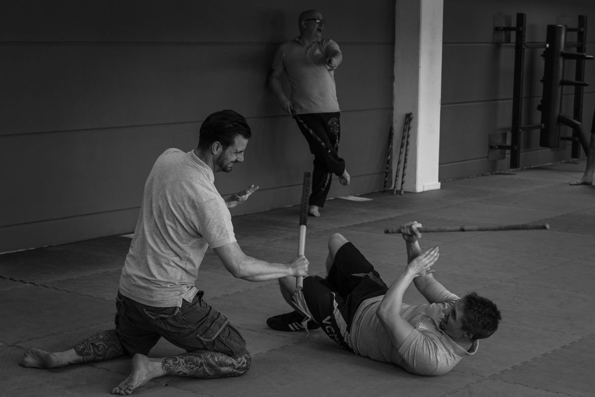 Zwei Kampftrainer und ein Schüler beim Üben auf der Matte