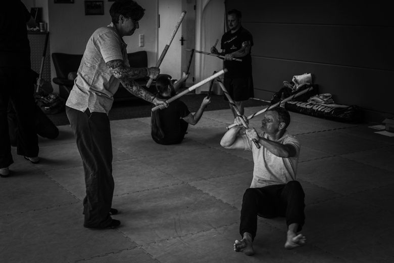 Zwei angehende Trainer üben sich im Stockkampf, während im Hintergrund auch ein Paar übt.