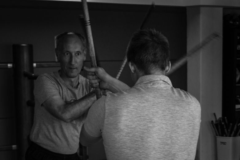 Zwei ältere Kampfsporttrainer demonstrieren konzentriert den Stockkampf