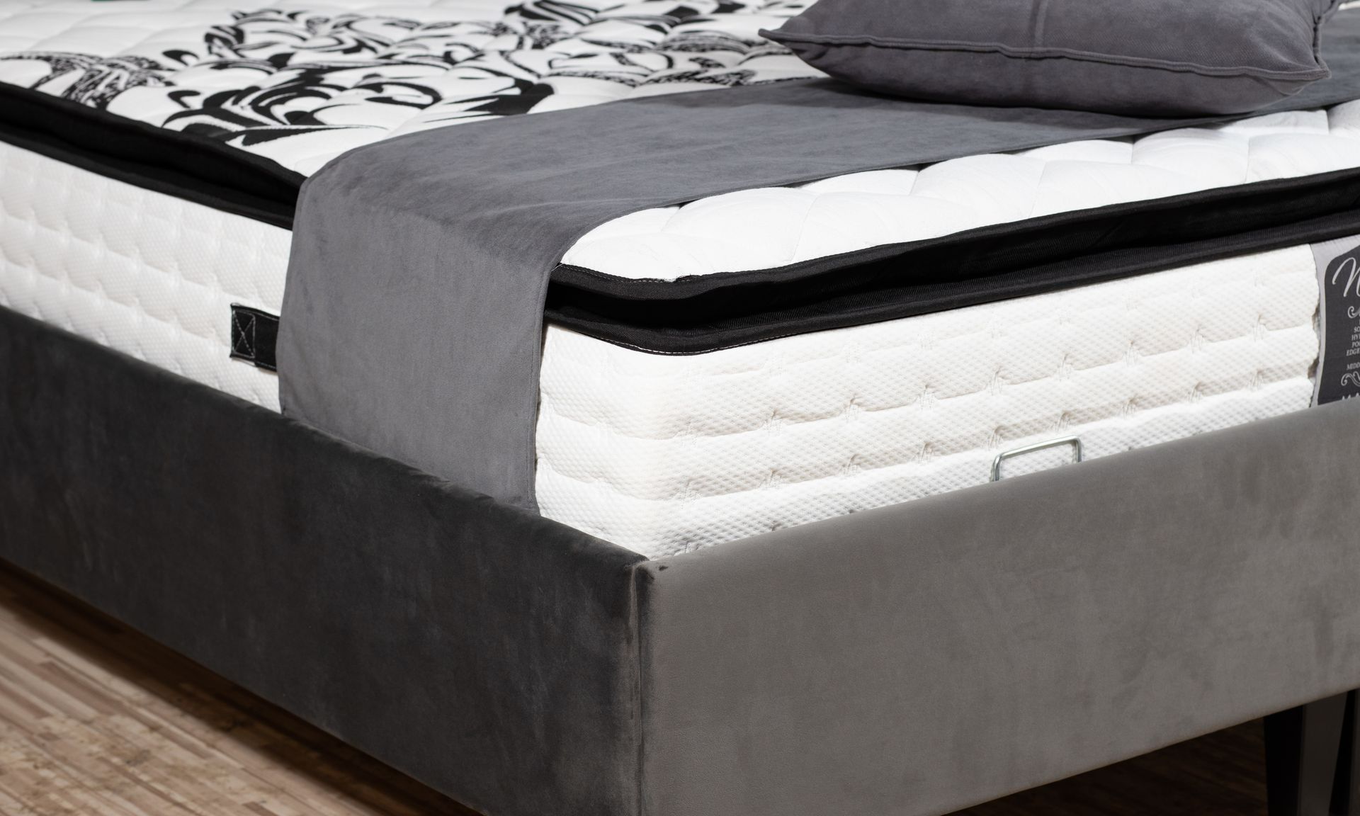 Un matelas épais avec des motifs baroques dans un cadre de lit en velours gris
