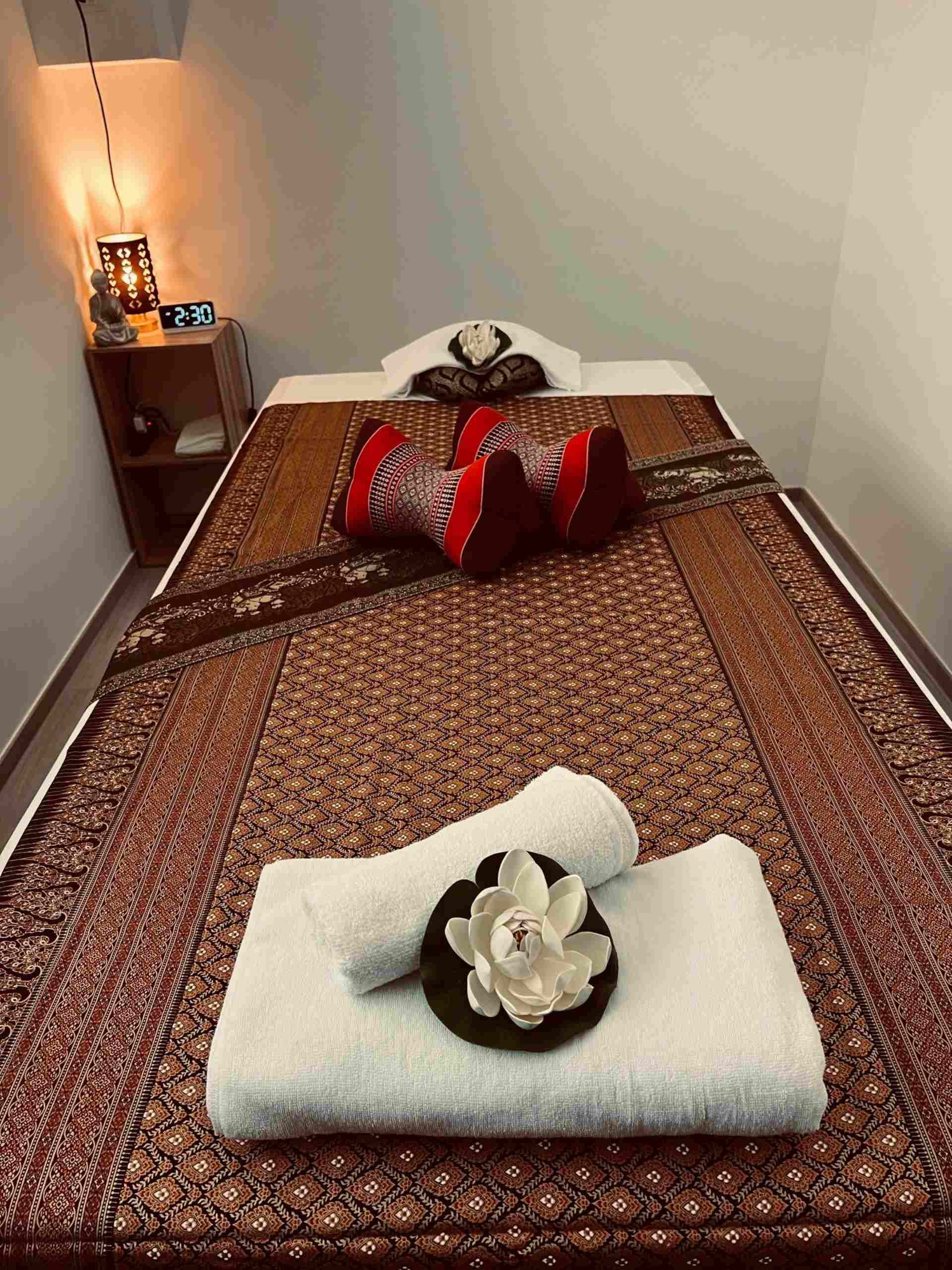 Une table de massage avec des serviettes et une fleur dessus dans une pièce.