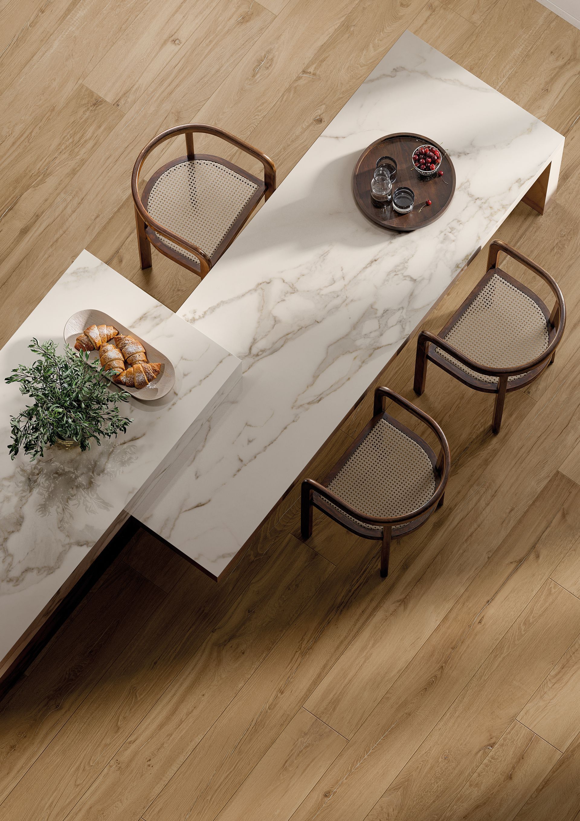 Vue de dessus d'une table à manger en marbre blanc avec des chaises en osier sur un parquet clair.