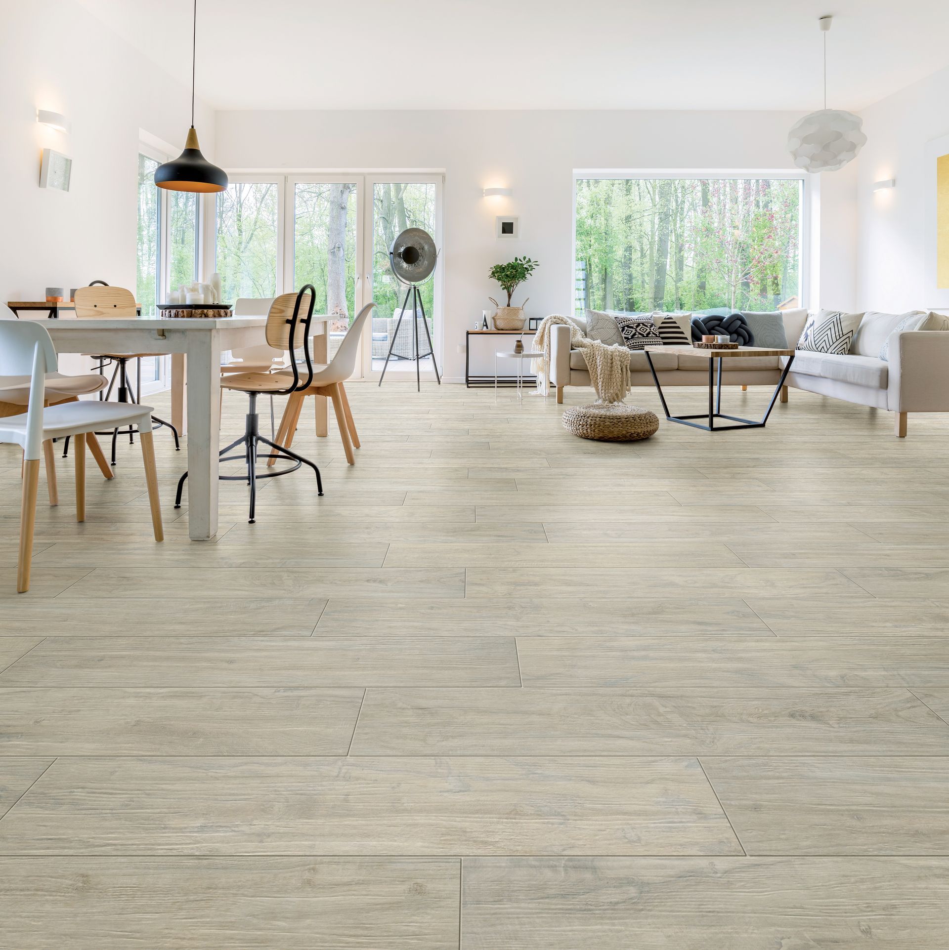 Salon lumineux et ouvert avec parquet clair, meubles blancs et grandes fenêtres