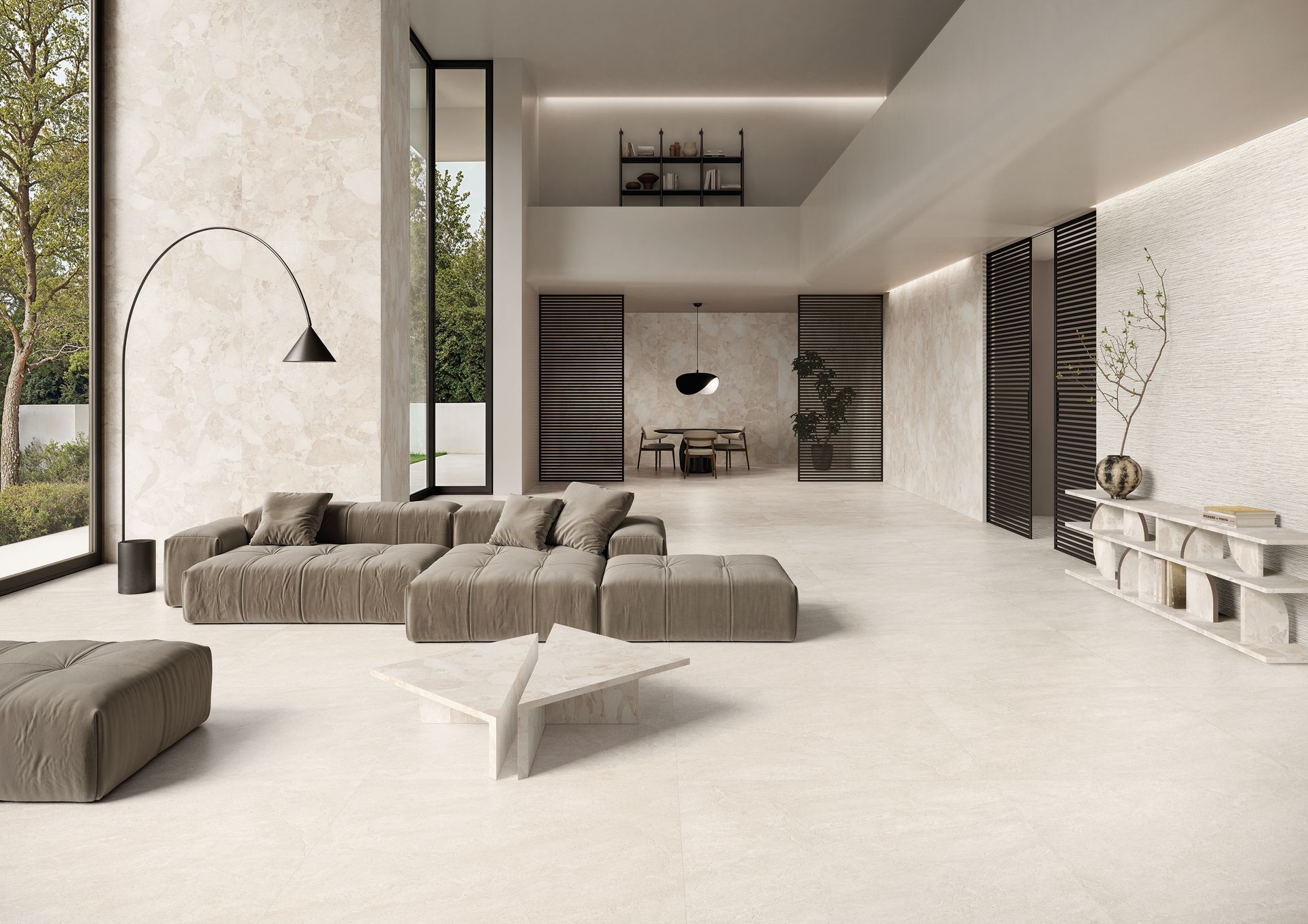 Salon minimaliste beige avec canapé d'angle, table basse, lampe arquée et mur multimédia