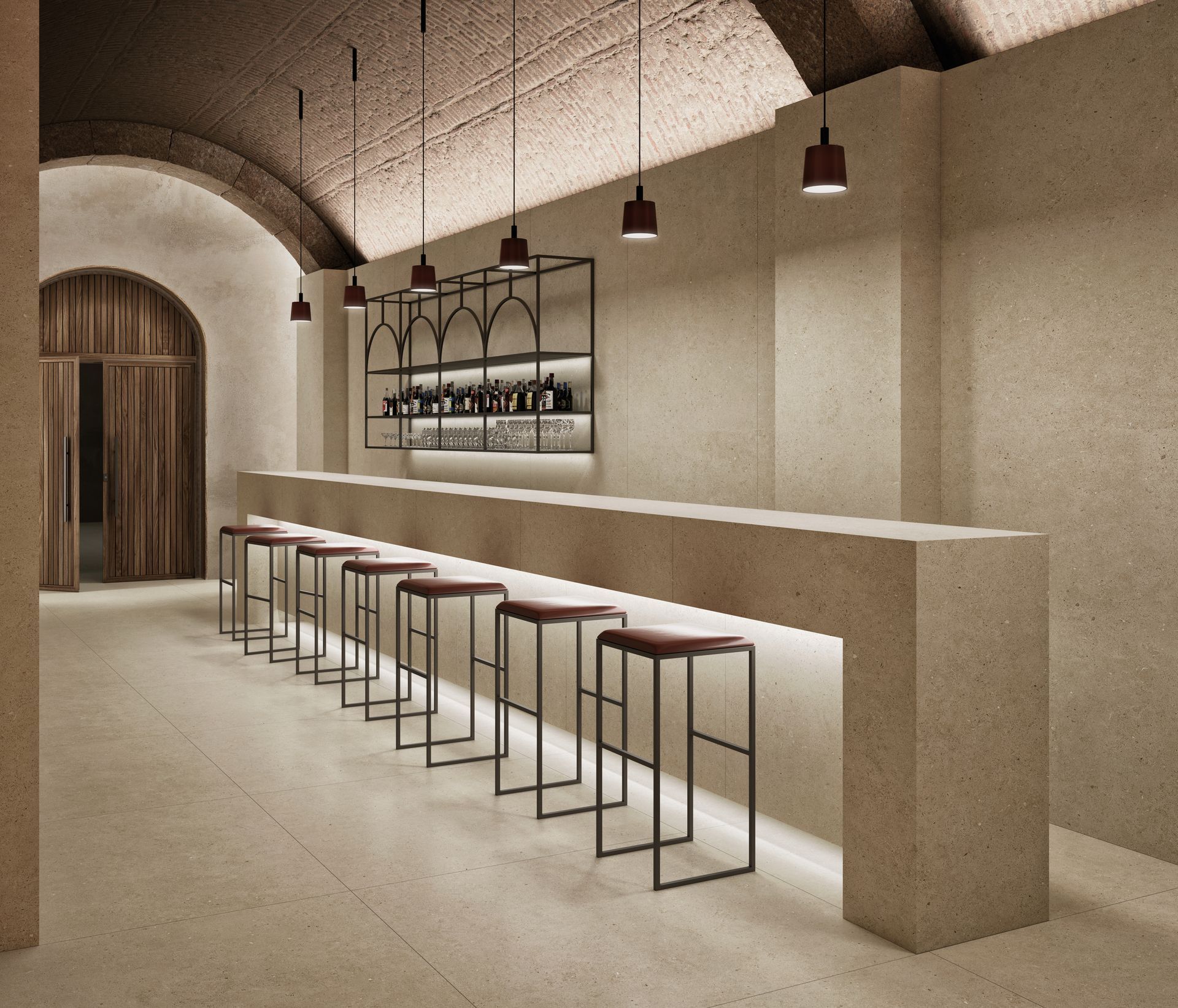 Intérieur de bar minimaliste beige avec un long comptoir, des tabourets en métal, des suspensions lumineuses et un plafond voûté.