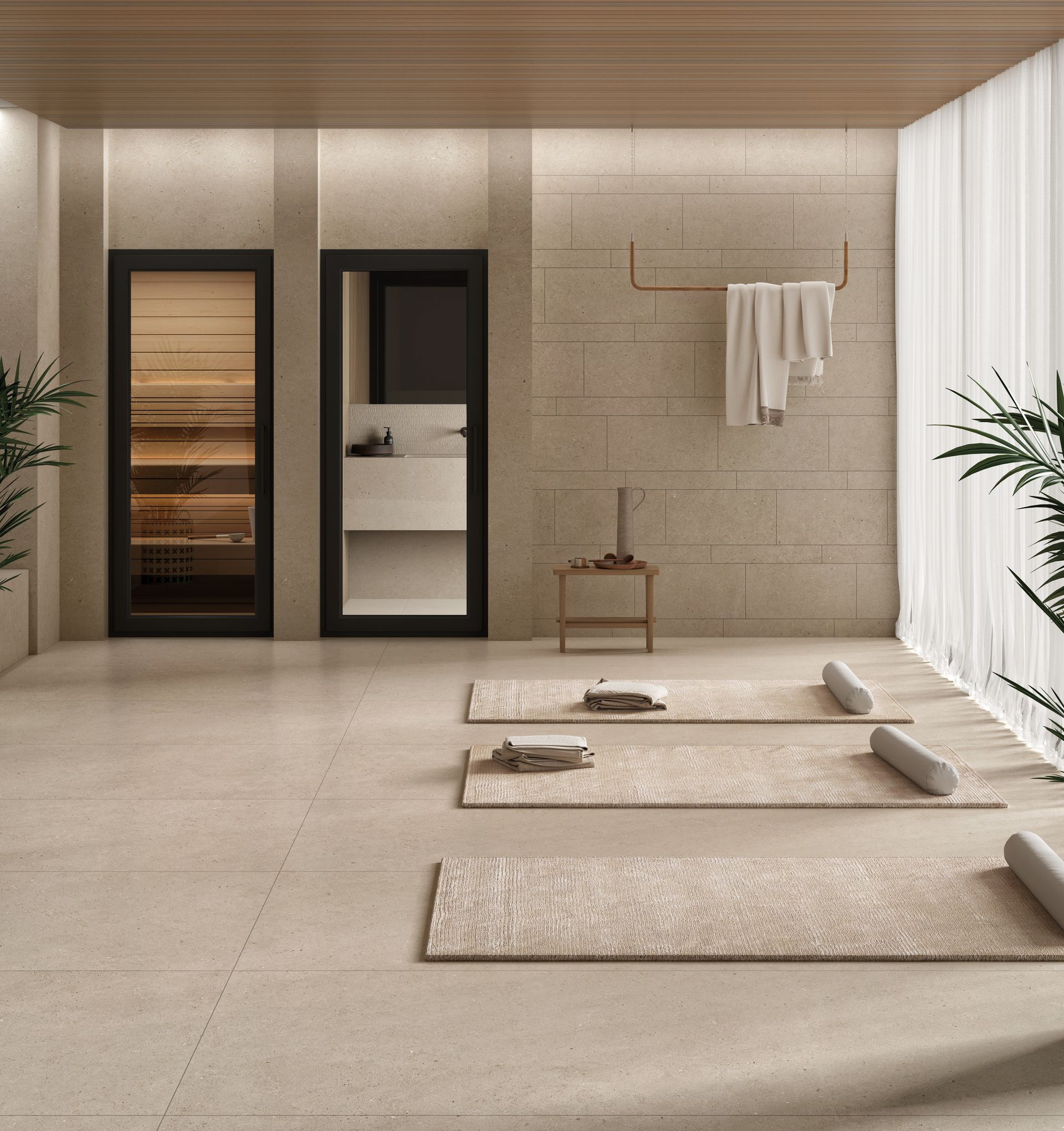 Salle de spa minimaliste avec tapis beiges, murs en pierre, serviettes suspendues et porte de douche en verre.
