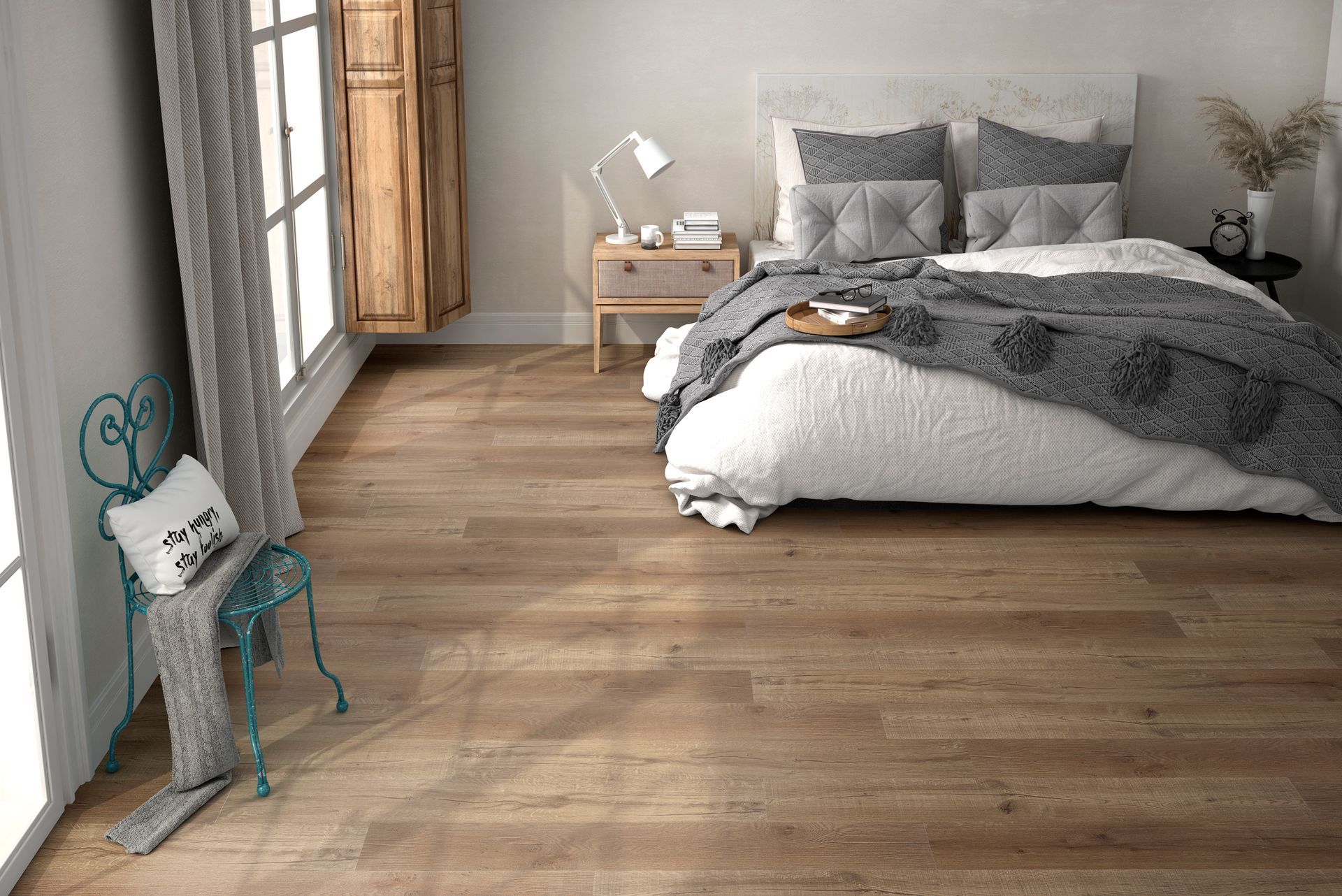 Chambre minimaliste avec un lit gris, un parquet et une chaise près de la fenêtre.